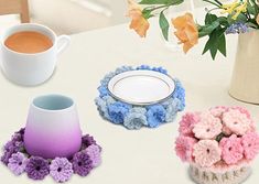 three crocheted coasters and a coffee cup on a table with flowers in the background