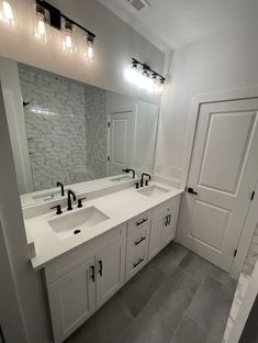 a large bathroom with two sinks and mirrors on the wall next to it's doors