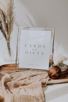 a thank card sitting on top of a table next to a vase with dried grass