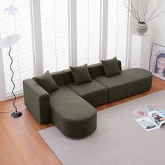 a large green couch sitting on top of a hard wood floor next to a window