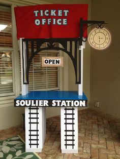 a train ticket office sitting on top of a blue counter next to a clock and window