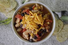 a white bowl filled with chicken and black bean chili next to tortilla chips