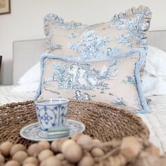 a cup and saucer sitting on top of a bed next to two pillows,