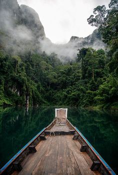 there is a boat that is going down the river with mountains in the back ground