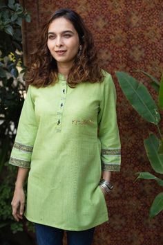 Tailored out of the finest weave of 100% premium South Cotton, aarchi promises breathable comfort and a rich organic texture signature to this luxe fabric. The rich green color of top is contrasted with dainty highlights of kalamkari on the 3/4th sleeves and the yoke. The collar neck is highlighted with handwork following the elegant 3/4th sleeves. Green Cotton Dress, Indian Kurti Designs, Indian Kurti, Short Kurti, Cotton Kurti Designs, A Line Kurta, Cotton Kurti, Collar Neck, Rich Green