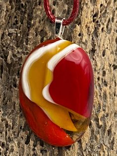 a red, yellow and white pendant hangs on a rock