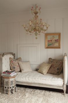 a white day bed sitting in a bedroom next to a chandelier