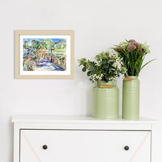 two green vases with flowers on top of a white dresser next to a painting