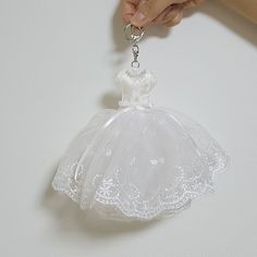 a hand holding a key chain with a white dress on it