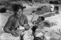 an old black and white photo of people laying on the ground with babies in their lap