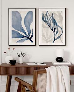 two paintings hanging on the wall above a desk