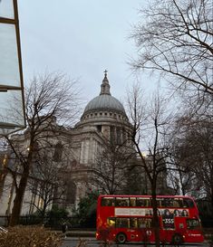 a red double decker bus parked in front of a building with a dome on top