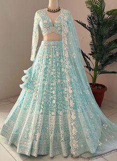 a light blue lehenga with white lace on the bottom and sleeves, in front of