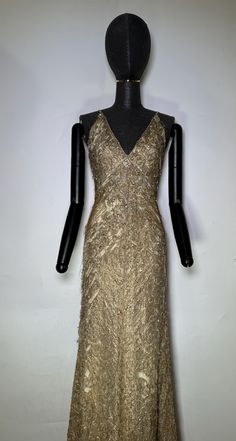 a gold dress on display in a room with white walls and black mannequins