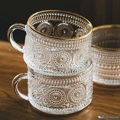 three glass mugs sitting on top of a wooden table next to eachother