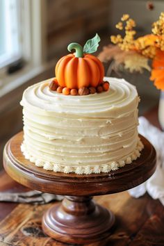 a cake with frosting and pumpkin decorations on top is sitting on a wooden table