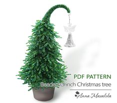 a green christmas tree with an angel ornament hanging from it's side