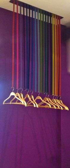 there is a row of clothes hangers with colored ribbons hanging from the hooks in front of them