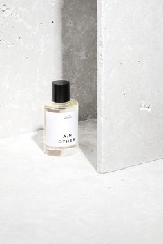 an open bottle of cologne sitting on top of a white counter next to a cement block