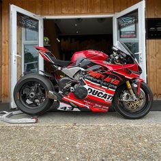 a red motorcycle parked in front of a garage