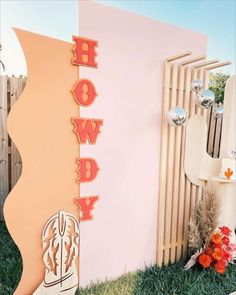 a sign that says hollywood next to a wall with flowers and decorations on it in front of a fence