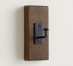 a wooden door handle on a white wall with a black latch and an iron hook