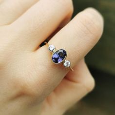 A fantastic vintage three stone ring, set with an oval Tanzanite to the centre, flanked either side by a round brilliant-cut diamond, weighing an estimated 0.10ct each, rub-over set in 18ct yellow and white gold.Hallmarked as 18ct gold, dated London 1993.The diamonds measure an approximate 0.10 carats each.The tanzanite in the setting measures approximately 8 x 5mm.The approximate weight is 2.1 grams.Please note that the vintage ring box pictured is for display purposes only. Thank you.Ring size Reset Ideas, Ruby Ring Designs, Vintage Ring Box, Diamond Three Stone Ring, Gold Pearl Ring, Tanzanite Diamond Ring, Antique Diamond Rings, Tanzanite Diamond, Three Stone Ring