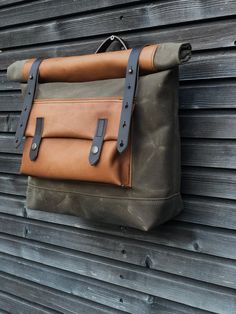 a brown and black bag hanging on the side of a wooden building next to a wall