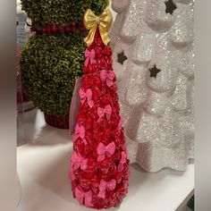 a red and pink christmas tree made out of fake flowers on a white counter top