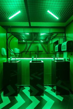 a bathroom with two sinks and green lights on the ceiling above it is a black and white checkered floor