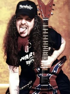 a man with long hair holding a guitar in front of his face and tongue out