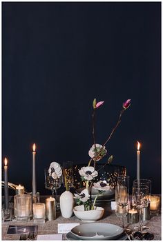 the table is set with candles, plates and flowers in vases on top of it