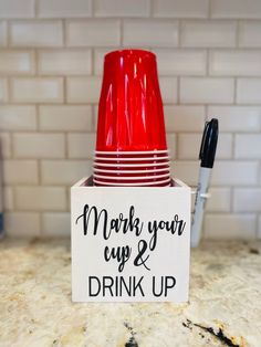 a stack of red cups sitting on top of a counter next to a marker board