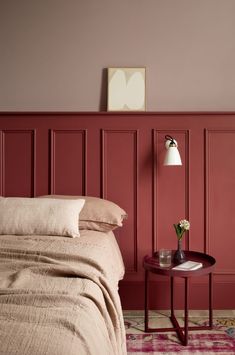 a bedroom with red walls and a bed in the corner next to a small table