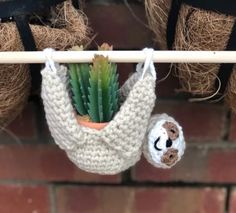 a crocheted sloth hanging from a clothesline with a cactus in it