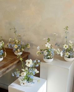 three white vases with blue and white flowers in them