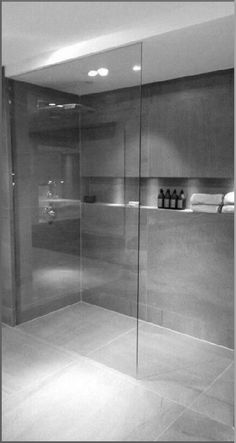 a glass shower door in a bathroom next to a sink and toilet paper dispenser