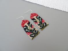 a pair of red and black beaded mittens hanging from a hook on a gray surface