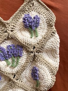 a crocheted bag with purple flowers on it