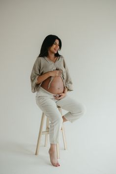 a pregnant woman sitting on top of a stool