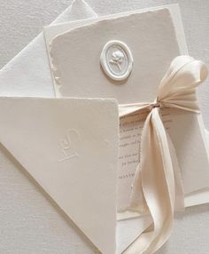 an envelope with a button and ribbon tied around the front is laying on top of two folded cards