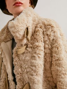 A fur jacket with a fluffy and voluminous silhouette that creates a romantic atmosphere. The front can be fastened with a band, and the high neck design protects your neck from the cold. 
 
 
 
 
 Size 
 
 
 S size 
 
 Length: 69cm 
 Shoulder width: 45cm 
 Bust: 116cm 
 Sleeve length: 55cm 
 
 M size 
 
 Length: 70cm 
 Shoulder width: 46cm 
 Bust: 120cm 
 Sleeve length: 56cm 
 
 
 
 
 
 Material 
 
 Polyester 
 
 
 Model worn 
 
 Wearing size 
 
 S size 
 
 Model dimensions 
 
 Height: 170cm 
 B Chic Fur Coat With Faux Fur Lining, Chic Cold Weather Fur Coat With Faux Fur Trim, Faux Fur Coat With Faux Fur Lining, Sheepskin Fur Coat In Beige For Cold Weather, Chic Shearling Fur Coat For Cold Weather, Fluffy Beige Fur Coat For Fall, Mink Colored Shearling Fur Coat With Faux Fur Trim, Fluffy Mink Outerwear For Cold Weather, Beige Shearling Fur Coat For Winter