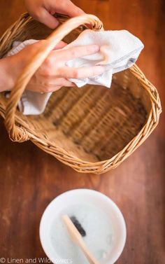 a person is cleaning a basket with a cloth and a wooden spoon on the table