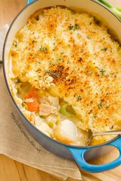 a casserole with chicken and vegetables in a blue dish on a wooden table