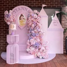 there is a pink and purple flower display on the floor in front of a brick wall