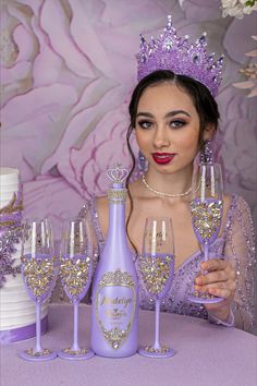 a woman wearing a tiara and holding up wine glasses in front of a cake