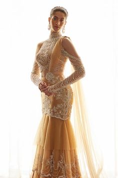 Beige mermaid silhouette layered lehenga saree with astron bloom embroidery using pearls, bugle beads, crystals, sequins, aari highlights. Paired with a halter neck blouse with all over Royal pearl crystal embellishments and long cold shoulder sleeves detailing. - Aza Fashions Floor-length Dresses With Sheer Sleeves For Reception, Festive Reception Dress With Sheer Sleeves, Fitted Evening Dress With Traditional Drape, Glamorous Semi-stitched Dresses With Traditional Drape, Glamorous Semi-stitched Dress With Sheer Dupatta, Traditional Drape Embellished Evening Dress For Reception, Embellished Evening Dress For Reception With Traditional Drape, Fitted Bollywood Gown Hand Embellished, Designer Embellished Fitted Dresses