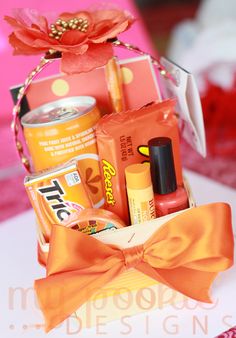 an orange bow is tied around a basket filled with cosmetics and personal care products on a table