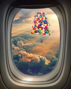 an airplane window with balloons floating in the sky