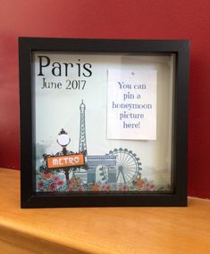 an advertisement for the paris film festival is displayed in a frame on a wooden table